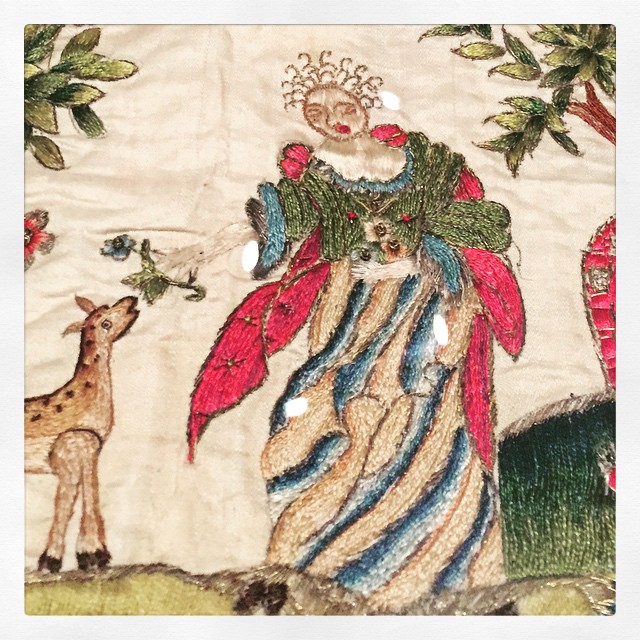 embroidery of a lady with excellent hair feeding some sort of four legged creature