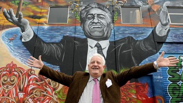 franco cozzo standing with his arms spread in front of a mural of franco cozzo
