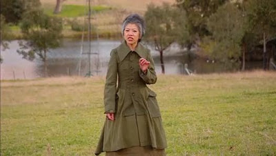 LLC in an amazing green coat with puffy peplum, standing in a field